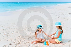 UV protection. Sister puts sunscreen on her little sister`s nose