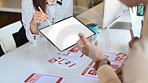 Ux developer and ui designer are using tablet and discussing ideas for new project.