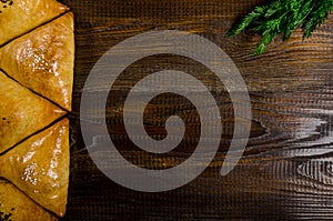 Uzbek national dish of samsa with herbs on a dark wooden background, place for inscription