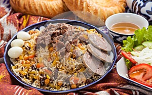 Uzbek national food pilaf on traditional fabric adras