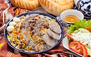 Uzbek national food pilaf on traditional fabric adras