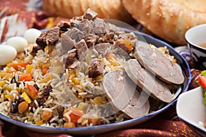 Uzbek national food pilaf on traditional fabric adras