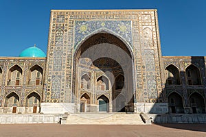 Uzbek religious architecture in facade of ancient Tilya-Kori madrasah with colorful ornament on brick walls