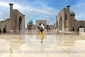 Uzbekistan, Samarcanda - young girl standing with open arms looking Registan square photo
