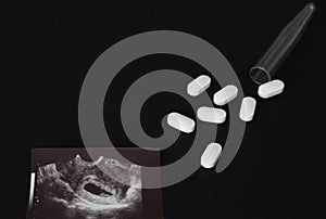 Uzi shot, pills and test tube on a black background, abortion, close-up