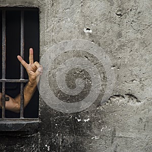 V sign (victory sign) a man behind bars. Background.