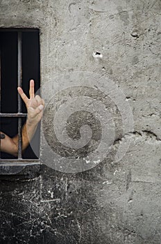 V sign (victory sign) a man behind bars. Background.