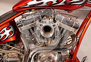 V-type two-cylinder motorcycle engine with chrome coating. Orange motorcycle frame with white flames.