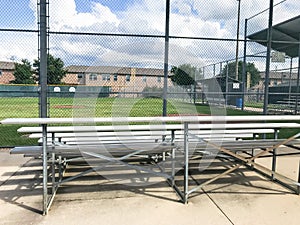 Vacant bleachers near empty baseball field with metal chain link in Dallas, Texas, USA