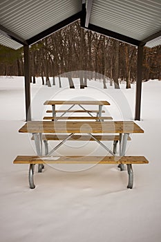 Vacant wooden table and benches in snow