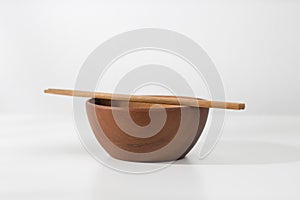A vacant wooden bowl and chopsticks.