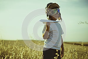 Vacation, Boy playing to be airplane pilot, funny guy with aviator cap and glasses, carries in his hand a plane made of paper