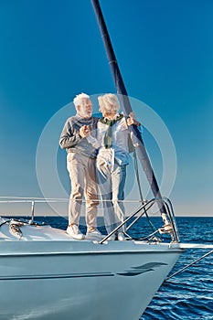 Vacation. Full length of happy senior couple in love holding hands and looking at each other while standing on the side