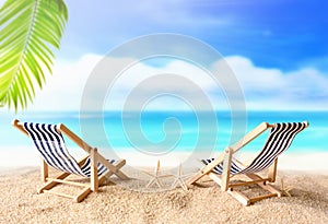 Vacation holidays background concept - two beach lounge chairs under palm on summer beach.