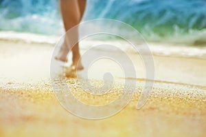 Vacation holidays concept - silhouette of sun-tanned woman legs shoeless that walks along seashore.