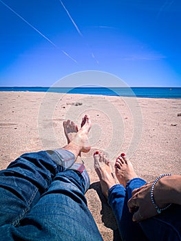 Vacation holidays. Man and woman feet closeup relxing on beach on sunbed enjoying sun on sunny summer day.