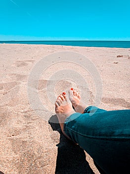 Vacation holidays. Woman feet closeup relxing on beach on sunbed enjoying sun on sunny summer day.