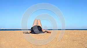 Relaxing holidays. Woman in a hat closeup relaxing on beach on a sand, having a sunbed, enjoying sun on sunny summer day