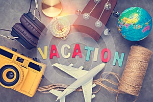 vacation ideas concept with travel stuffs camera ukulele headphone,plane,globe,compass with wwoden text word on grey leather back