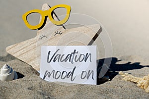 VACATION MOOD ON text on paper greeting card on background of beach chair lounge starfish summer vacation decor. Sandy