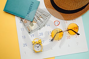 Vacation planning concept. Travel preparation: sunglasses, passport and vacation plan marked in calendar on yellow blue