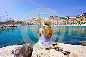 Vacation relax. Girl sitting on stone enjoying landscape of French Riviera on sunny day, Menton, France