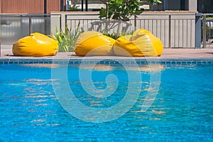 Vacation and Relaxation Concept : Three yellow mattress on edge of swimming pool in the resort.