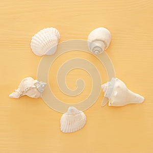 vacation and summer image with seashells over yellow wooden background.