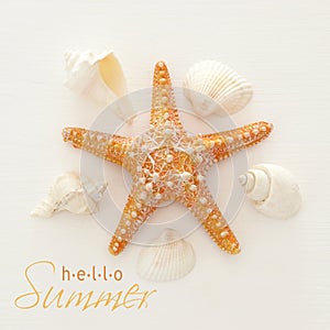 vacation and summer image with starfish and seashells over white wooden background.