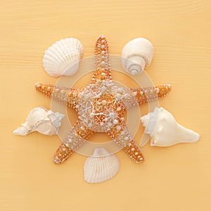 vacation and summer image with starfish and seashells over yellow wooden background.