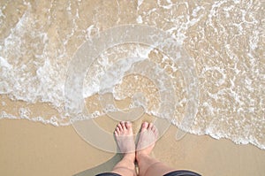 Vacation on summer ocean beach, feet on sea sand with bubble float wave