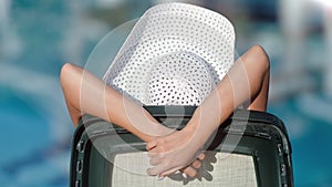 Vacation tanned person in white hat relaxing on deck chair enjoying sunbathing back view