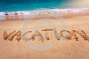 Vacation text on a beach. Vacation written in a sandy tropical beach. Vacation written in the sand on the beach blue waves in
