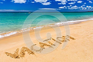 Vacation text on a beach. Vacation written in a sandy tropical beach. Vacation written in the sand on the beach blue waves in