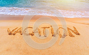 Vacation text on a beach. Vacation written in a sandy tropical beach. Vacation written in the sand on the beach blue waves in