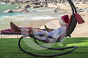 Vacation in Thailand, a young man lies on a sunbed in a Santa hat at a beach resort