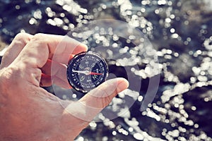 Vacation time. Hiking. Summer holidays. Time to travel. Travelling. Male hand holding compass. Sea waves on background