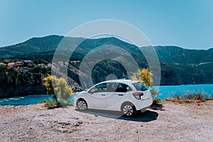 Vacation travel with car concept. Rental hired car in front of amazing bay with turquoise water. Discover Mediterranean Islands.