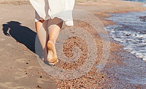 Vacation travel - woman leg closeup walking on white sand relaxing in beach cover-up pareo beachwear. and tanned legs. Sunmme