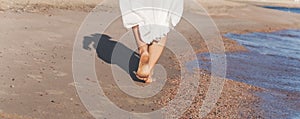 Vacation travel - woman leg closeup walking on white sand relaxing in beach cover-up pareo beachwear. and tanned legs. Sunmme