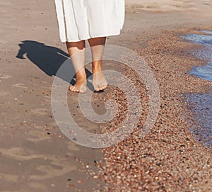 Vacation travel - woman leg closeup walking on white sand relaxing in beach cover-up pareo beachwear. and tanned legs. Sunmme