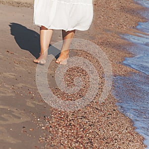 vacation travel - woman leg closeup walking on white sand relaxing in beach cover-up pareo beachwear. and tanned legs.