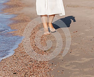 vacation travel - woman leg closeup walking on white sand relaxing in beach cover-up pareo beachwear. and tanned legs.