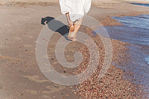 vacation travel - woman leg closeup walking on white sand relaxing in beach cover-up pareo beachwear. and tanned legs.