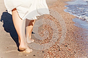 Vacation travel - woman leg closeup walking on white sand relaxing in beach cover-up pareo beachwear. and tanned legs. Sunmme