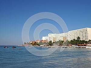 Vacation view of white hotels buildings on sandy beach at bay of Caribbean Sea in Cancun city in Mexico with tourists