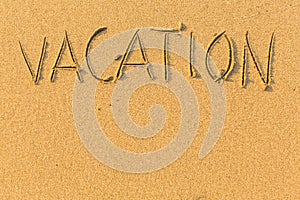 Vacation - word drawn on the sand beach. Abstract.