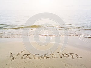 Vacation written in a sandy tropical beach. Words written in sand against the sea in sunny day. Summer vacation weekend concept.