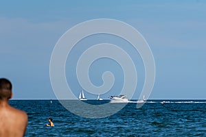 Vacationer against the sea with a boat and a sail ships