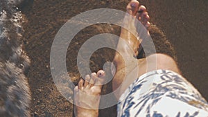 Vacationer walking along the sea coast and waves washing his feet